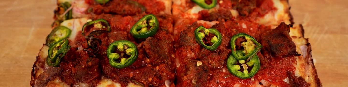 Closeup of Motown Square's Tibs Pizza showing jalapenos, cheese and sauce.