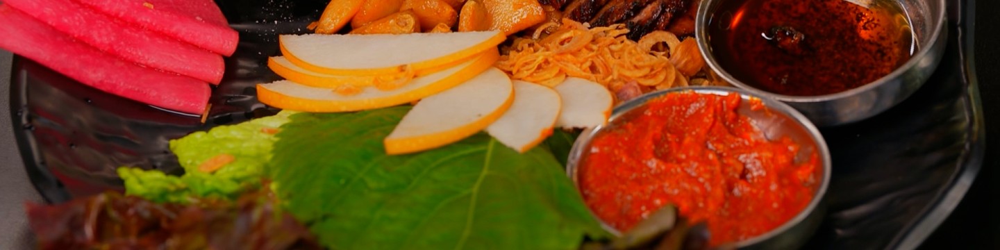 Close up of Anju ssam board featuring marinated short ribs and vegetables.