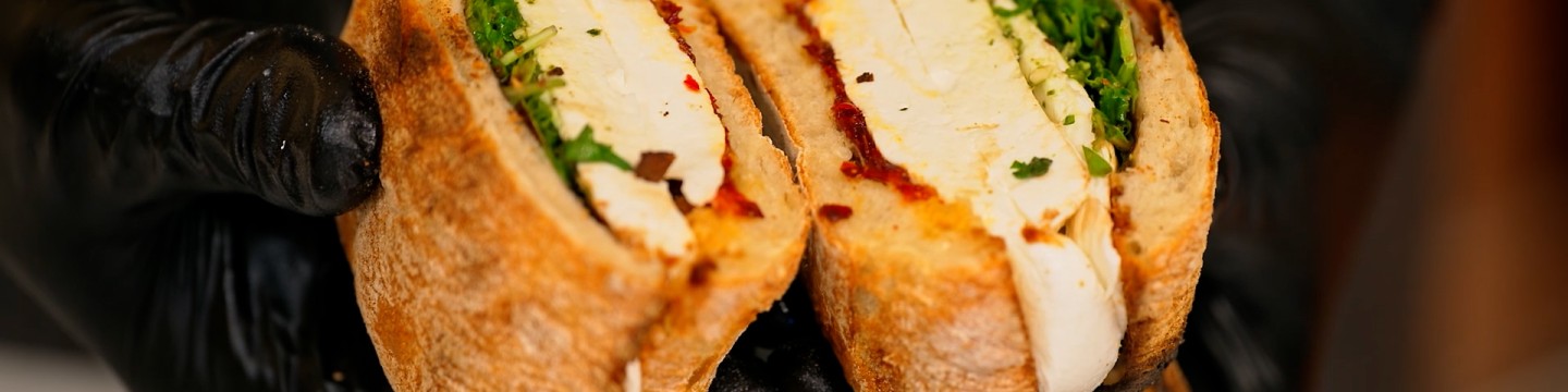 Two hands holding caprese sandwich cut down the middle.